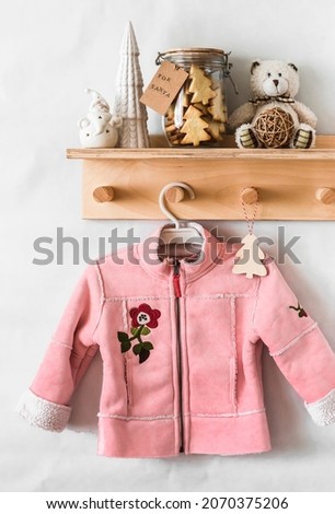 Christmas interior of the children's room. Wooden shelf-hanger with a pink sheepskin coat for children in vintage style, a cookie jar for Santa, Christmas decorations