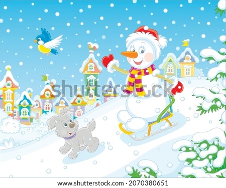 Happy little snowman and a merry small puppy cheerfully sledding down a snow hill on a playground in a snowy park of a pretty town on winter holidays, vector cartoon illustration