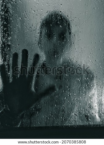 a man in a psychiatric hospital looks through wet glass. Horor photo