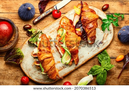 Fresh croissants,healthy breakfast on the kitchen board.Croissants with trout, meat bacon, vegetables and fruits Royalty-Free Stock Photo #2070386513