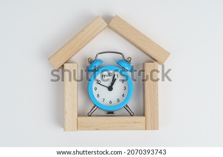 Time to buy a house, A gray house and black alarm clock on stone background Royalty-Free Stock Photo #2070393743