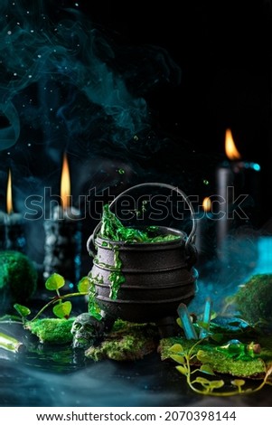 Witch cauldron with a green boiling bubble potion in the dark forest. Fairy tale. Witch craft.