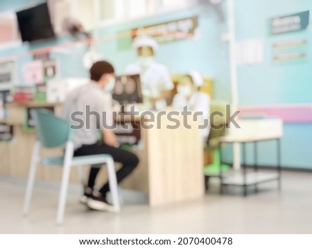 Blurred image of unidentified people and patients waiting to see the doctor at at reception desk with nurse in hospital during COVID-2019. Waiting medicine concept. 