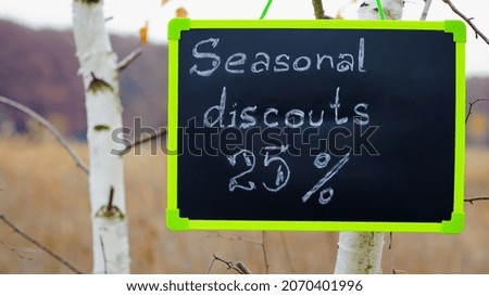 frame with text. seasonal, autumn discounts. Chalkboard and autumn leaves. natural background. the sign with the text weighs on the tree. close-up. sale, big discounts, 25 percent