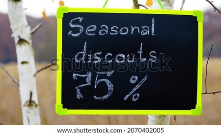 frame with text. seasonal, autumn discounts. Chalkboard and autumn leaves. natural background. the sign with the text weighs on the tree. close-up. 75 percent, sale, big discounts