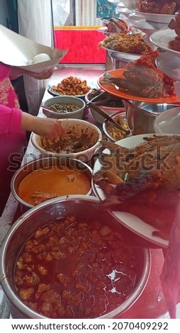 Asian woman preparing food for customer in Traditional "Nasi Padang" Restaurant. A lot of traditional dish called "Nasi Kapau"