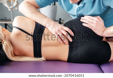 Treatment of sacroiliac joint dysfunction (SI joint pain) performed by osteopathic doctor, chiropractor applying manual procedures to lower back region Royalty-Free Stock Photo #2070416051