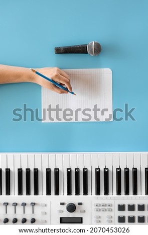 Musical keys, microphone and blank paper on a blue background.