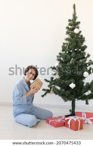 Young woman opens gifts under Christmas tree. Christmas and new year concept