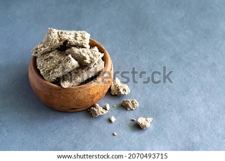 Sunflower halva in a clay plate on a gray background. Made from sunflower seeds. High quality photo