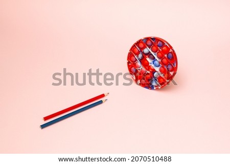 Pop it fidget toy and pencil in the same colour. Blue and red. Spiderman.