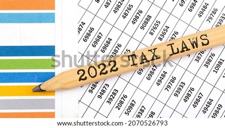 Business concept 2022 TAX LAWS text on the pencil on the chart background