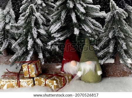 Little cute gnomes near christmas tree snow background with gifts
