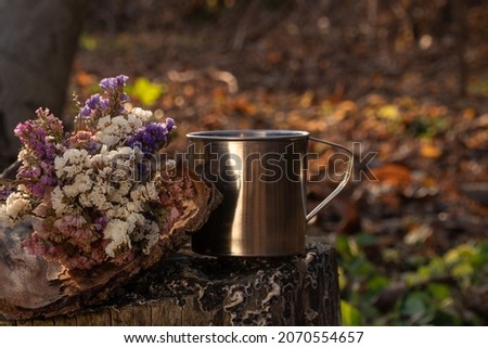 
a hot cup of tea stands on a wooden stand. a cup of steam stands in the autumn garden.