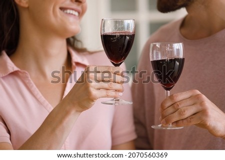 Close up happy loving affectionate couple man woman clinking glasses of red wine, enjoying romantic date, celebrating wedding anniversary or special occasion together at home, relations concept.