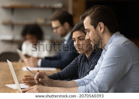 Focused two business people looking at computer screen, analyzing online sales, working on project, using corporate software applications, developing corporate growth strategy in office. Royalty-Free Stock Photo #2070560393