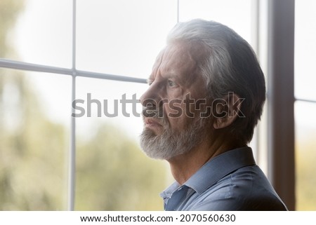 Old age problems. Worried concerned hoary elderly male pensioner stand alone look through window. Distressed confused aged grandfather feel lonely abandoned think of solitude on retirement. Copy space Royalty-Free Stock Photo #2070560630