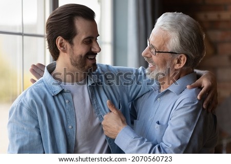 True friends. Excited elderly dad embrace adult son glad to hear good news congratulate with success show thumb up. Happy older age male proud of grown child achievement support approve young man deed Royalty-Free Stock Photo #2070560723