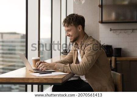 Happy young caucasian male manager working on computer in modern office, solving online project problems distantly, using software applications, typing message communicating with clients or colleagues Royalty-Free Stock Photo #2070561413
