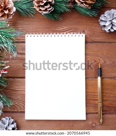 Notepad, pen and fir branches on a wooden table.