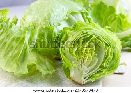 Fresh green iceberg lettuce salad leaves cut on light background on the table in the kitchen Royalty-Free Stock Photo #2070573473