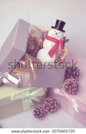 Pastel gray gift box with a snowman in side of it, gold colored  background
