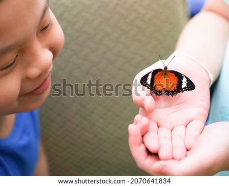 asian boy Make a happy face when you see a butterfly in someone else's hand.