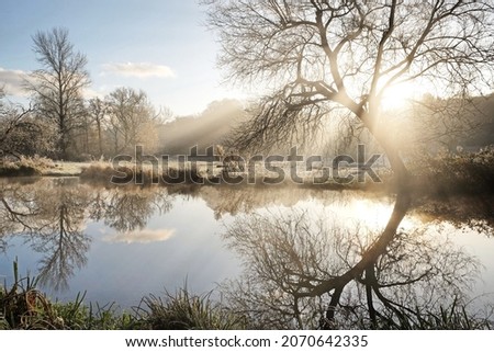 Sun flare and mist on the River Wey, Godalming, Surrey, UK Royalty-Free Stock Photo #2070642335