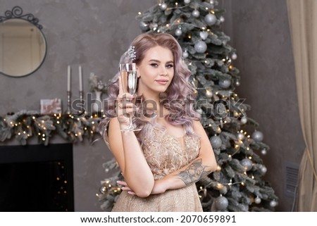 beautiful woman with a glass of champagne near the Christmas tree. New year concept.