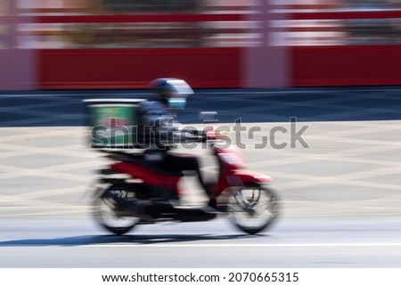 Delivery man on motorbike moving fast, blurred motion