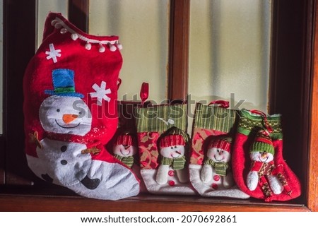 christmas concept with christmas socks,copy space to the left,christmas theme,snowman and santa claus,selective focus and window in the background