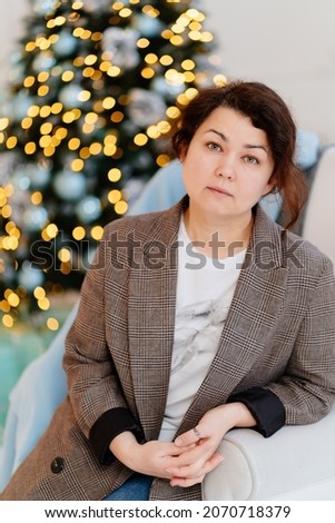 a brunette woman in a plaid jacket against the background of a christmas tree. designer services for New Year's decoration at home or in a photo studio.