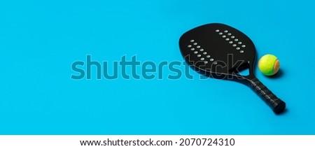 Black professional beach tennis racket and ball on blue  background. Horizontal sport theme poster, greeting cards, headers, website and app Royalty-Free Stock Photo #2070724310
