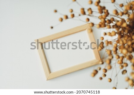 Photo frame mockup with blank paper card and dried flax on white background. Flat lay, top view, copy space.