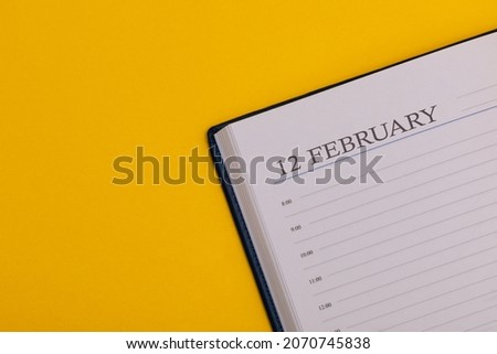 Notepad or diary with the exact date on a yellow background. Calendar for February 12 - winter time. Space for text.