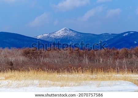 A high snow-capped mountain against the backdrop of a winter field. Sikhote-Alin Biosphere Reserve.