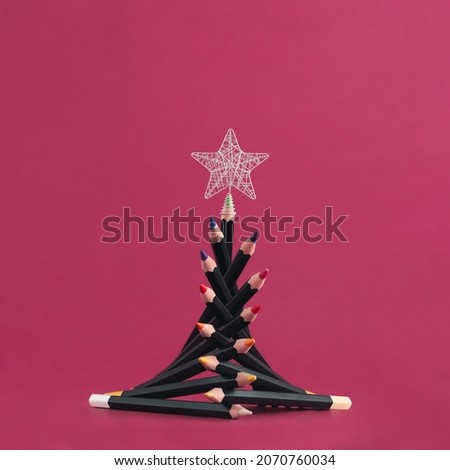 2023. Silver star and christmas tree with colorful wooden pencils isolated on red background. Minimal abstract concept of celebration in drawing school. Creative New Year greeting or gift card idea. Royalty-Free Stock Photo #2070760034