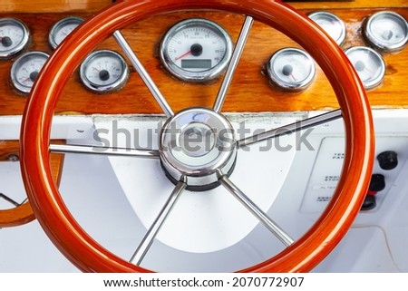 The cockpit of a luxury yacht with a classic, circular steering wheel and navigation equipment. Royalty-Free Stock Photo #2070772907
