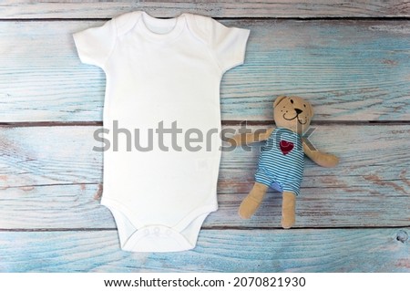 White baby bodysuit mockup on wooden background. Styled stock photography. Mock up