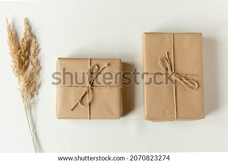 Two handmade Christmas presents . Gifts wrapped in craft paper and rope bow with pine tree branches as background. Royalty-Free Stock Photo #2070823274