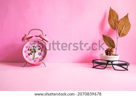 Product Presentation of Minimalist Concept Idea. glasses, alarm clock, dry leaves and pine flowers on pink paper background.
