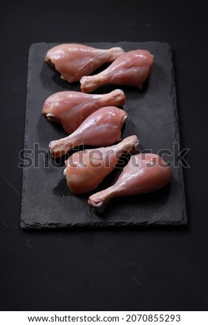 Raw chicken drum stick or leg pieces arranged on graphite sheet background