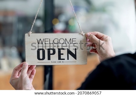 Closeup view of man hand holding open signboard hanging on window glass.