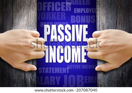 Hand opening a wooden door and found the "PASSIVE INCOME" word in the middle of many different words on blue background.