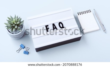 FAQ word on lightbox with notebook and pen, frequently asked questions concept