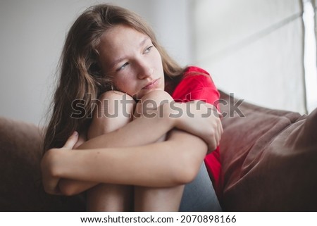 Depressed pensive bored teen girl introvert sitting on couch looking away suffer from loneliness, anxiety, psychological problem, feeling hurt sad apathetic lonely misunderstood concept