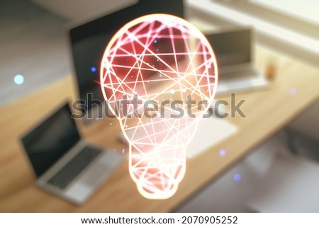 Double exposure of creative light bulb hologram and modern desktop with laptop on background, research and development concept