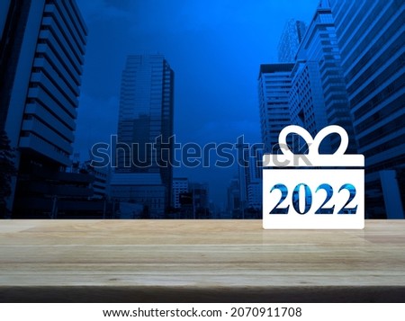 Gift box happy new year 2022 flat icon on wooden table over modern office city tower building and skyscraper, Business shop online concept