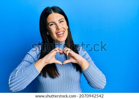 Beautiful brunette woman wearing casual clothes smiling in love doing heart symbol shape with hands. romantic concept. 