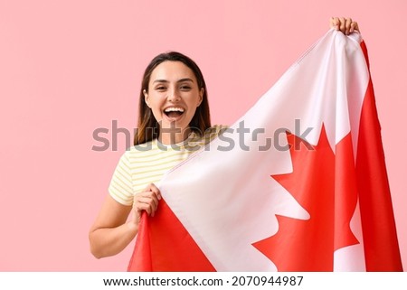 Beautiful young woman with flag of Canada on color background Royalty-Free Stock Photo #2070944987